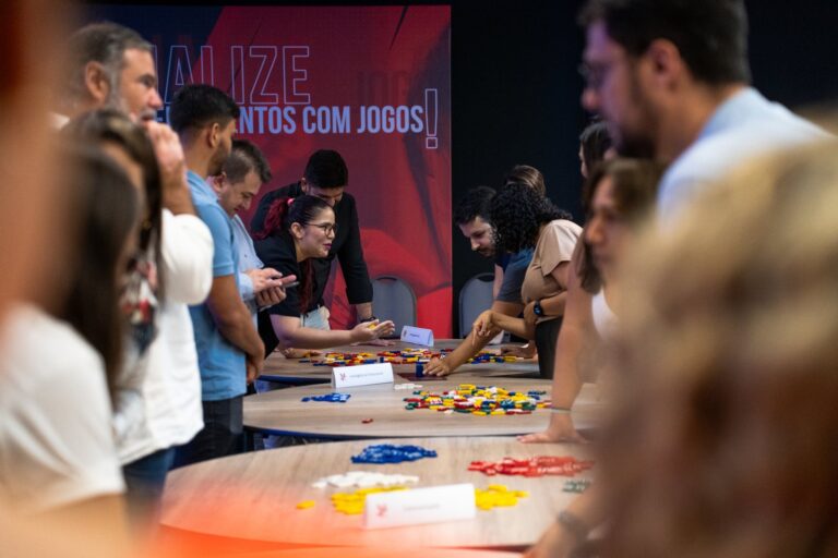 Participantes em uma dinâmica de jogos corporativos ao redor de uma mesa