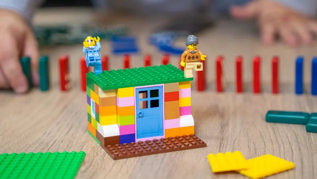 Casa montada com peças coloridas de montar sobre uma mesa de madeira
